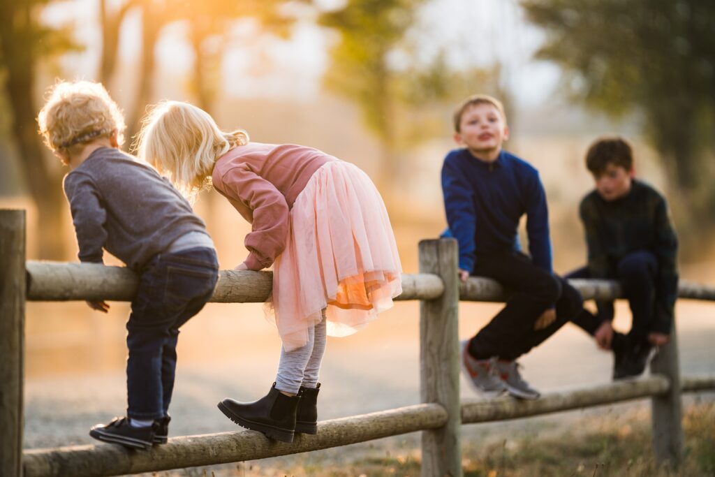 Four children on the fence in beautiful light during photos at Tanner Landing Park.