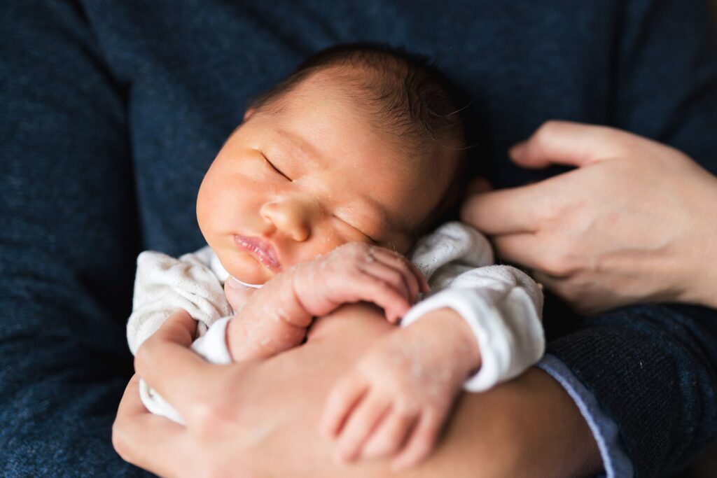 Newborn baby in father's arms during Issaquah newborn portraits