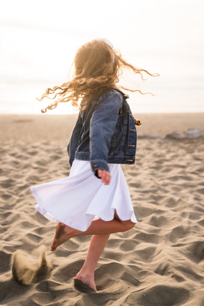 Girl twirling in the sand on the Washington Coast