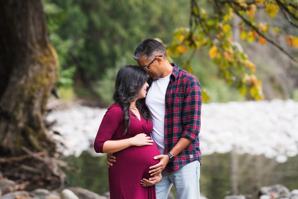Seattle area maternity pictures during fall, couple kissing near the river in North Bend, Wa