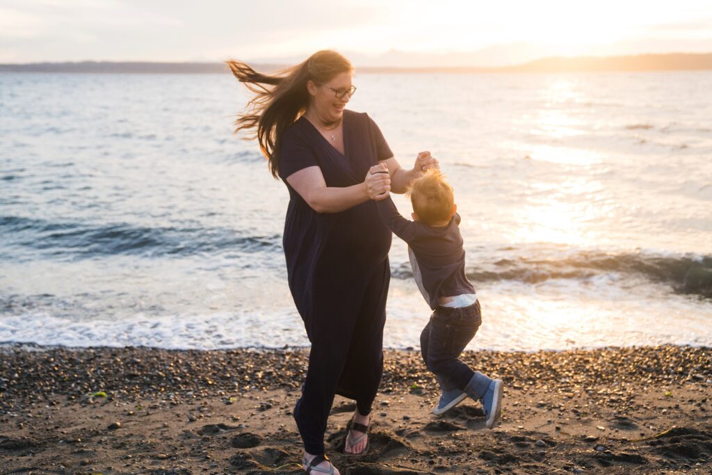 Mother playful spinning son at the beach at sunset in Seattle