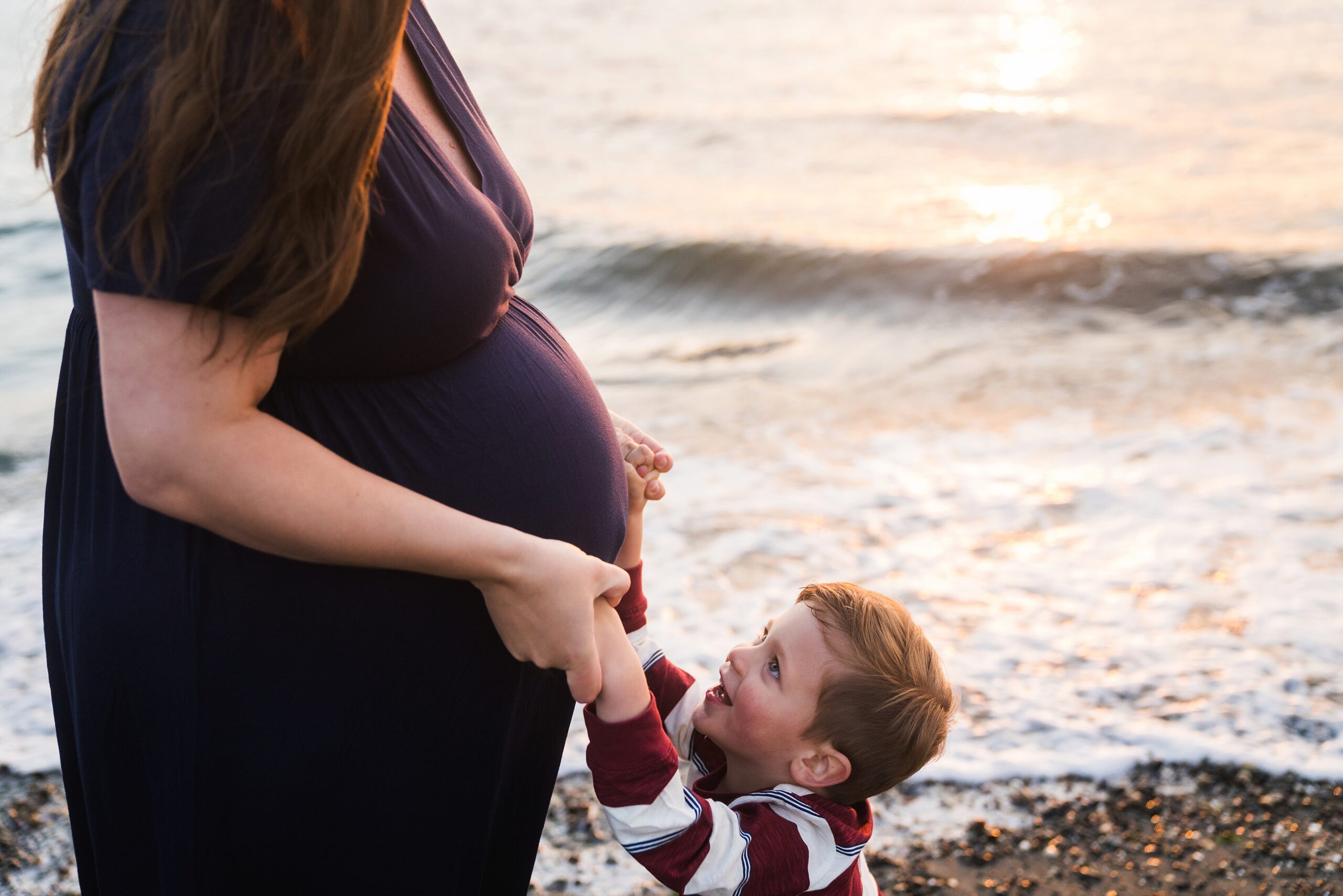 little boy feeling baby kicks on mommy during maternity pictures in Edmonds, Wa