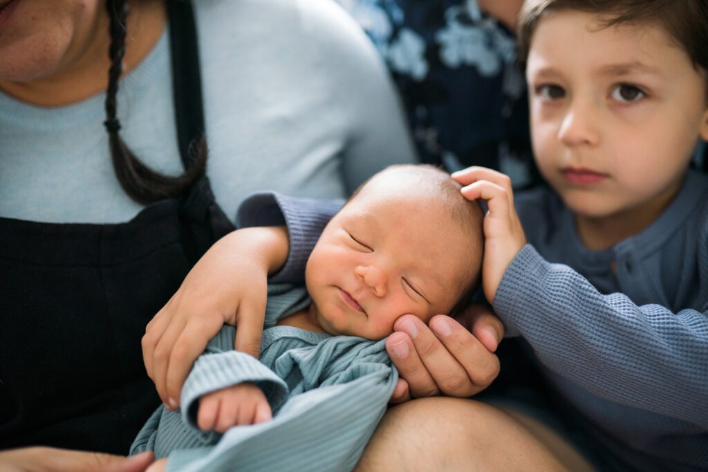 Mother holding baby boy as brother rubs his head during Seattle newborn photo session