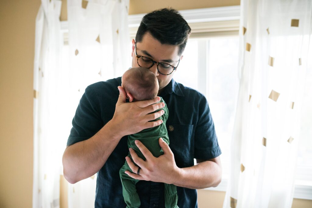 Father comforting newborn baby against his chest