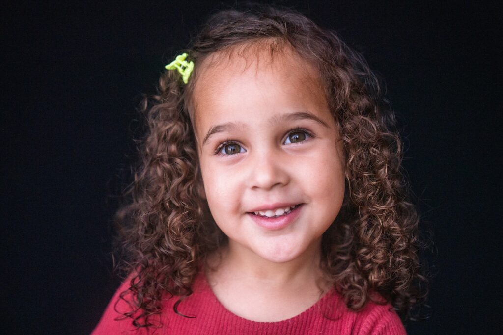 School picture day photo of girl with curls and small bow