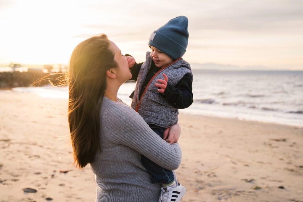 What to wear for fall maternity photos, pregnant mother holding toddler son on the beach in Seattle at sunset