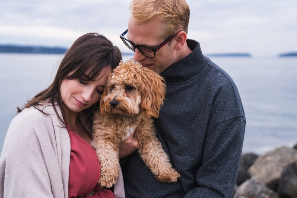 Family snuggled with dog for portrait session at Lighthouse beach park in Mukilteo