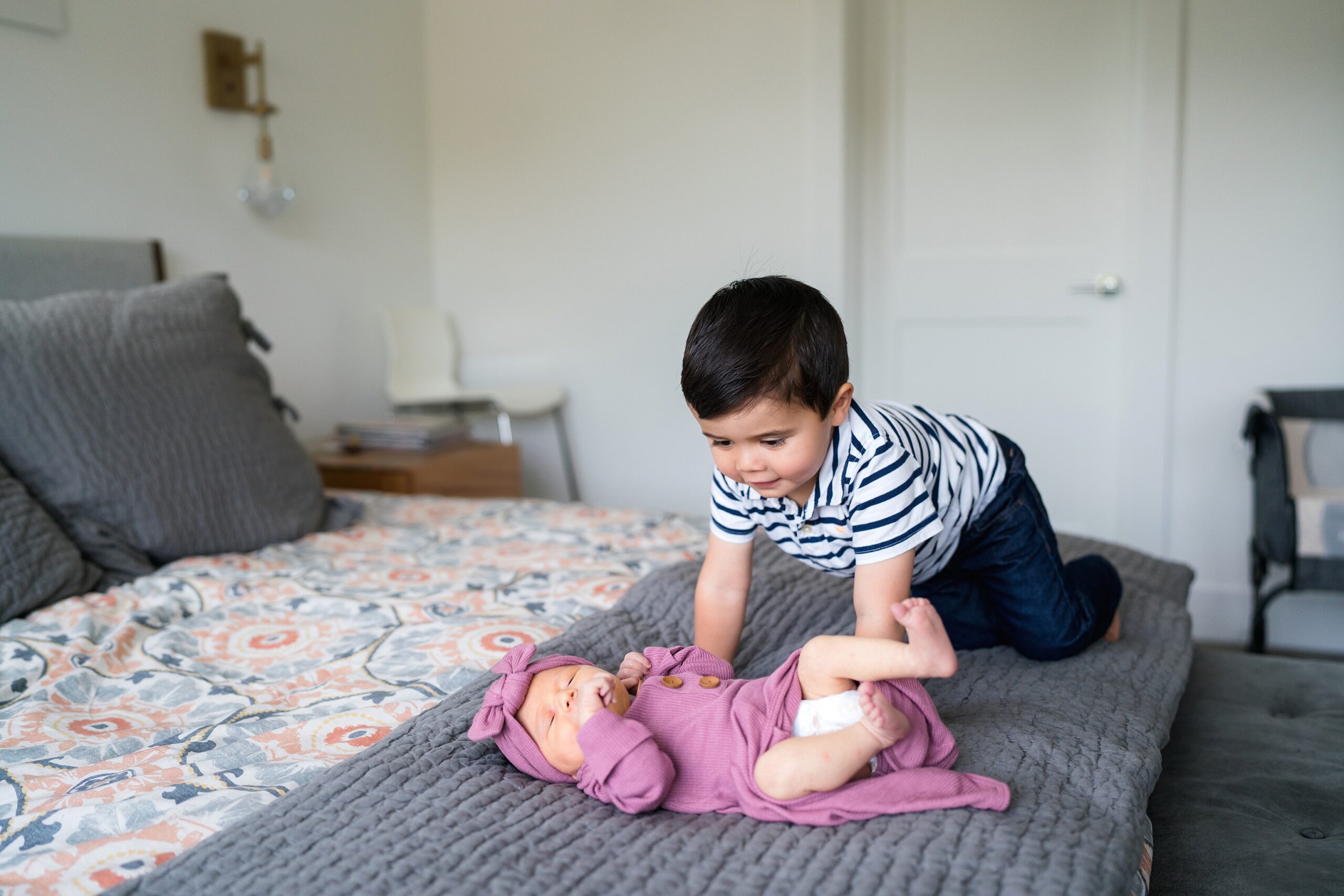 Big brother checking on baby sister during family photos with a newborn