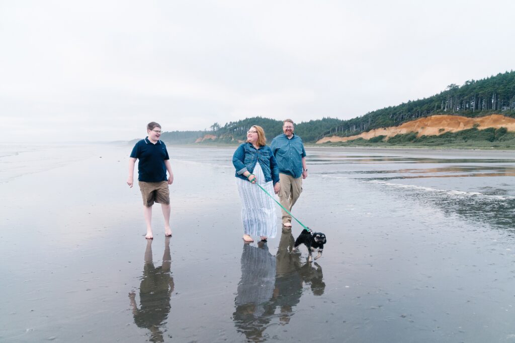 Family walking down the beach with their dog during family photos at the beach