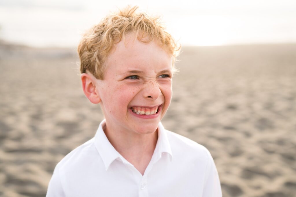 Boy smiling during family photoshoot at sunset, Ocean Shores, Wa