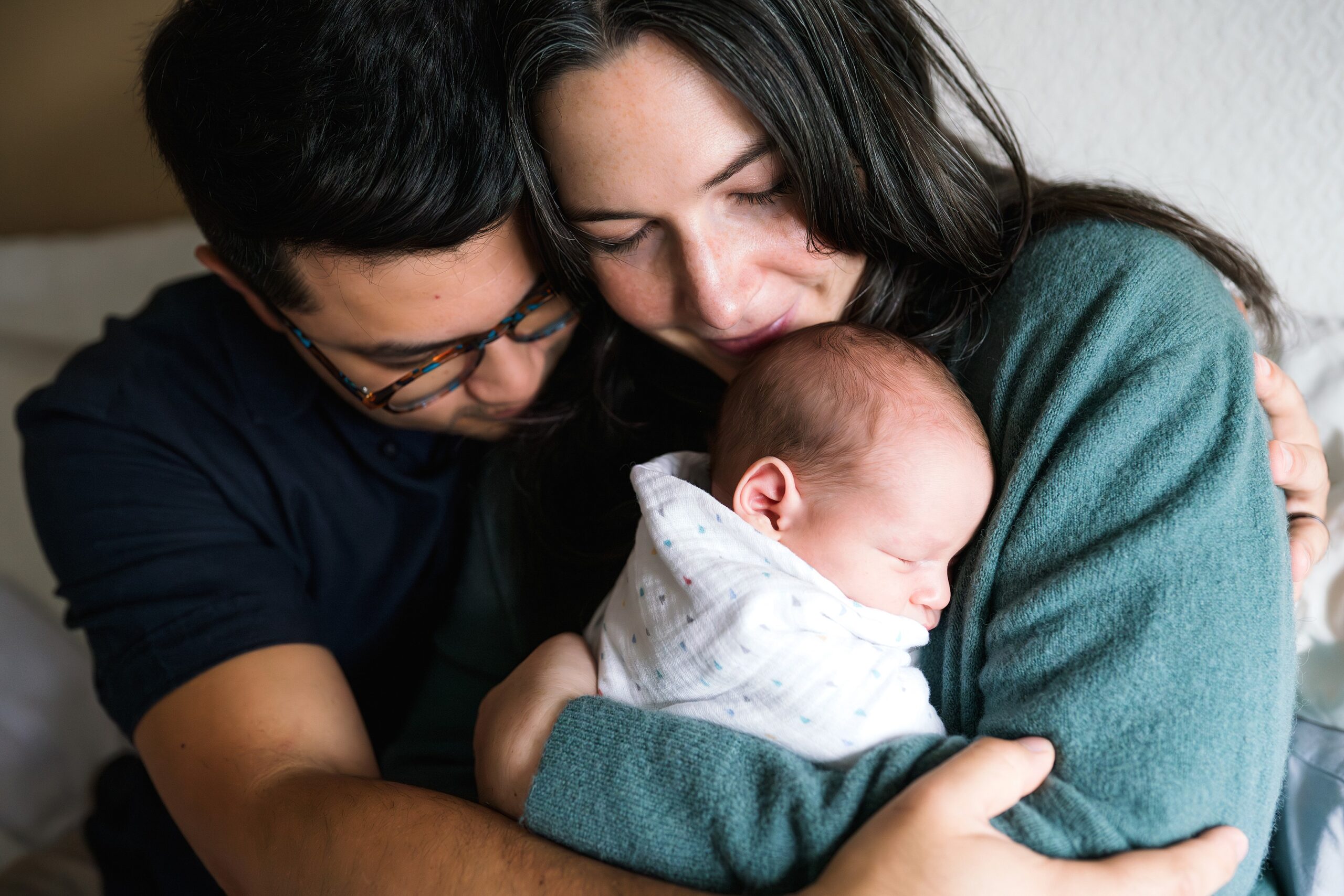 Seattle Newborn photo session at home with mother holding baby and father wrapped around them