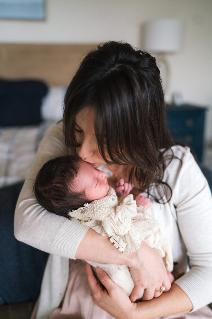 Mother kissing baby girl during relaxed Seattle lifestyle newborn photography session