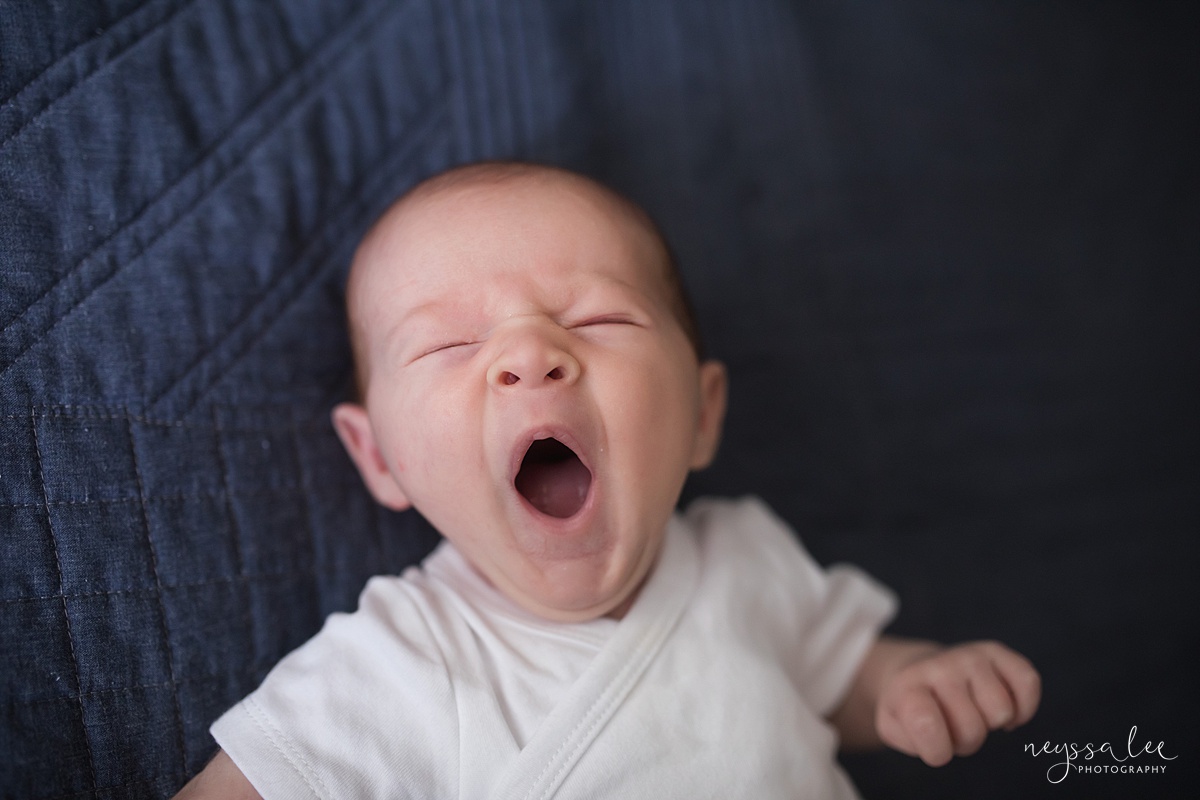 Yawning newborn in a well fitted oneise for outfit for newborn photos for in home Seattle photoshoot