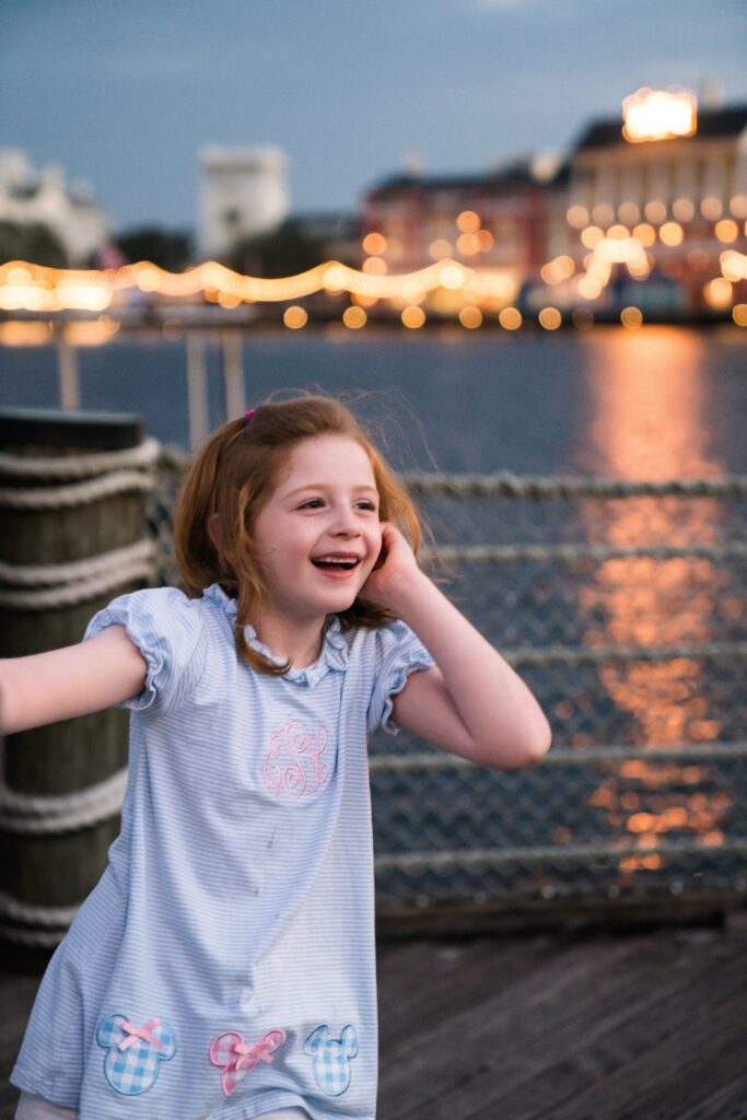 Girl at sunset at the Boardwalk in Disney with lights in the background