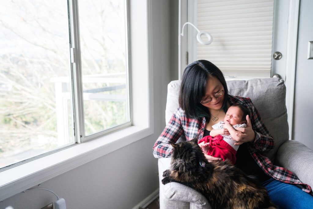 kitty cat sitting in rocking chair with mother and newborn baby during Seattle newborn photoshoot