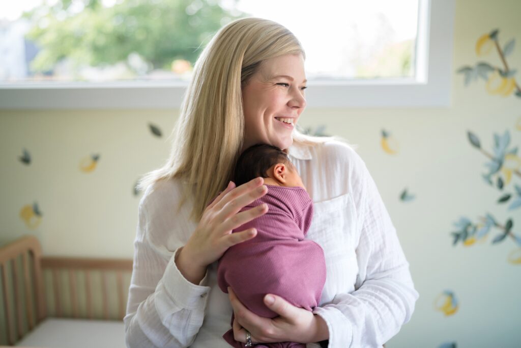 Mother with newborn daugther in lemon themed nursery during in home lifestyle Seattle photoshoot