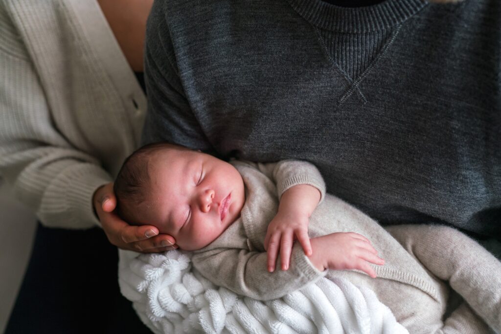 Natural newborn photo with baby in dad's arms and mother stroking baby's head