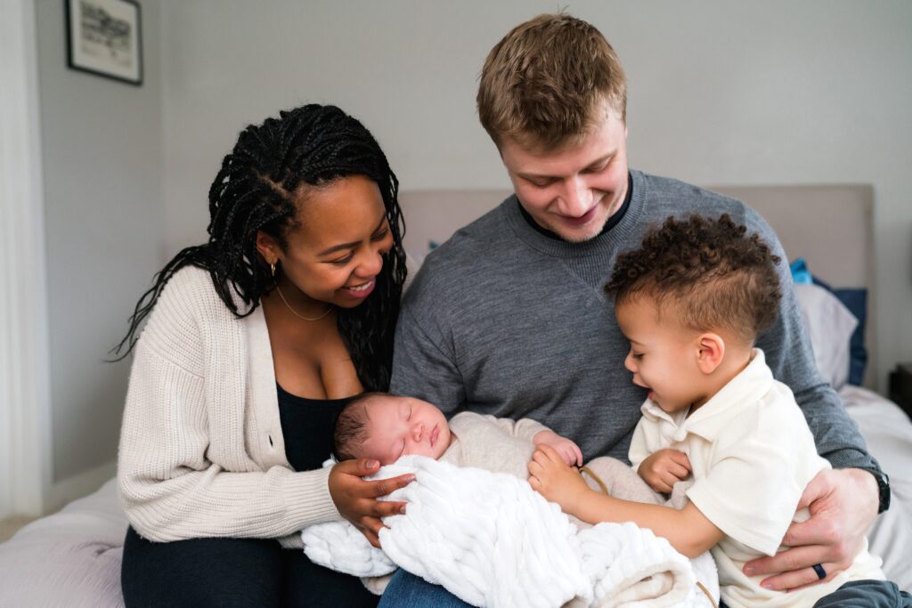 Seattle family snuggled with newborn baby boy and toddler boy for natural newborn photo