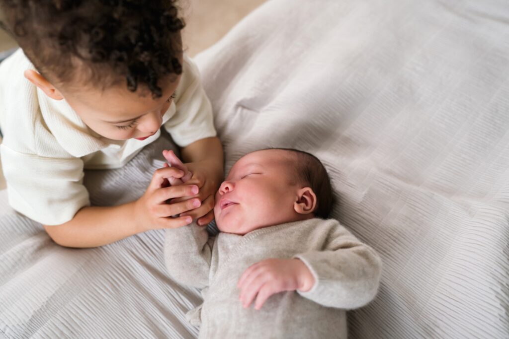 big brother holding baby brother's hand for a natural newborn photo