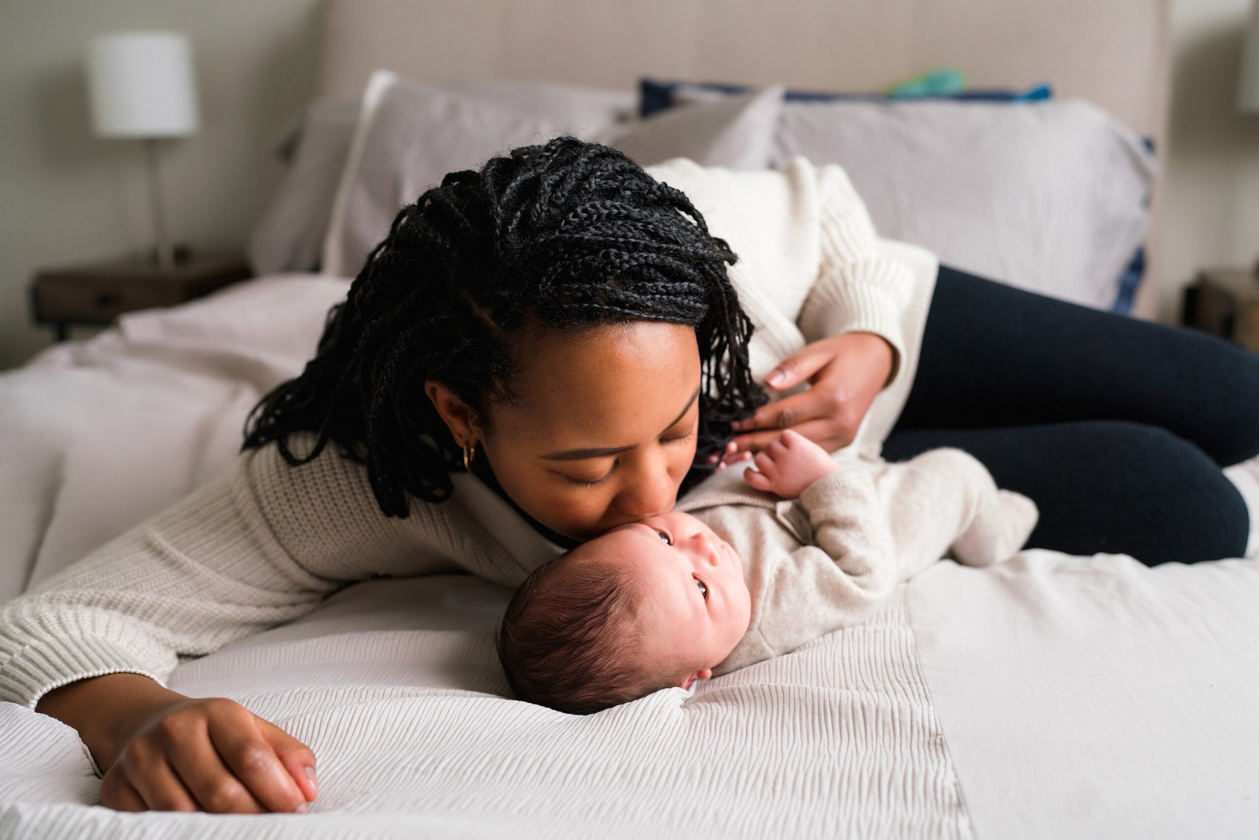 Mother laying with baby boy giving him a kiss during an in home Seattle newborn portrait session