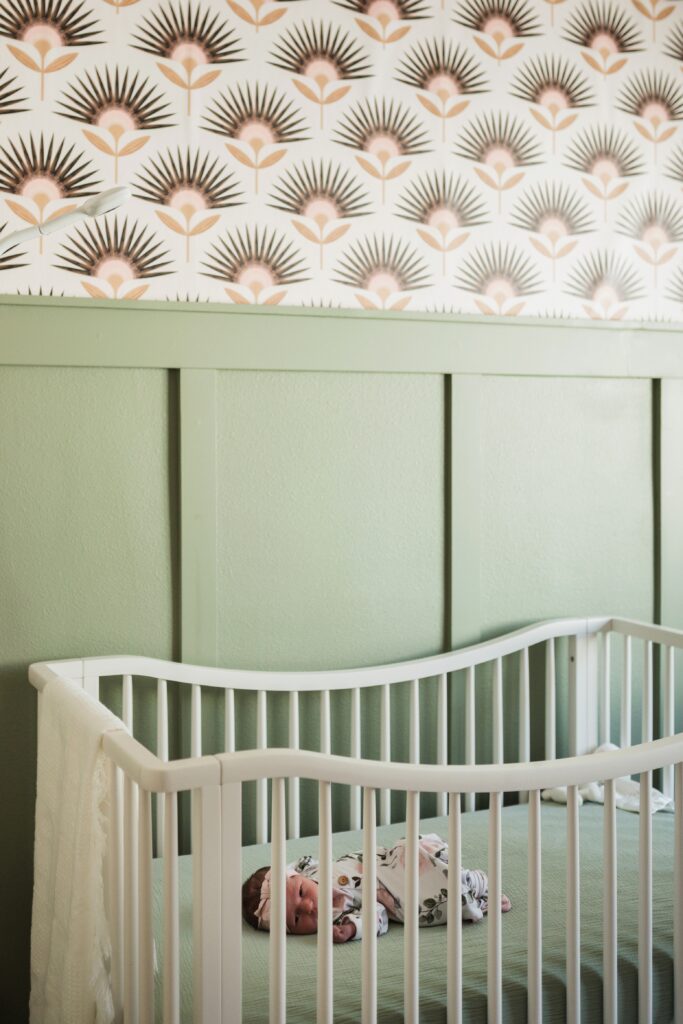 Baby girl in crib in green and floral nursery