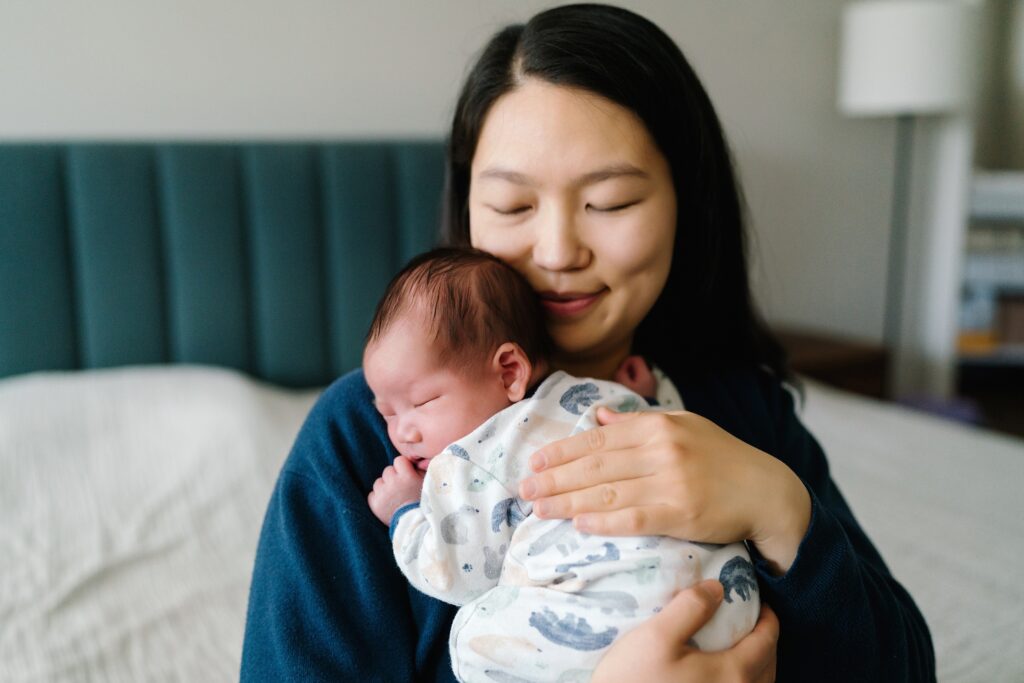 Mother holding newborn baby boy during in-home newborn photography session, Seattle maternity and newborn photos