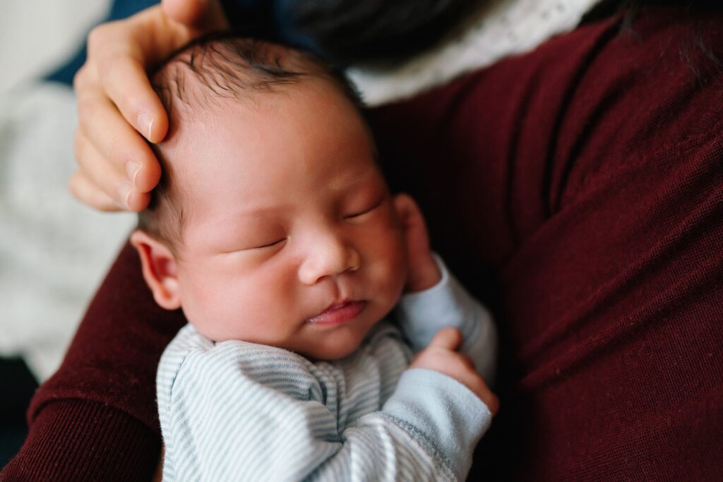 Newborn baby in mom and dad's arms during relaxed, in-home newborn photos