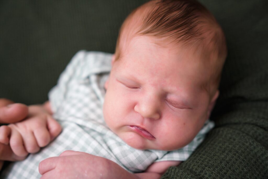 Newborn baby girl in father's arms for relaxed newborn photos booked early