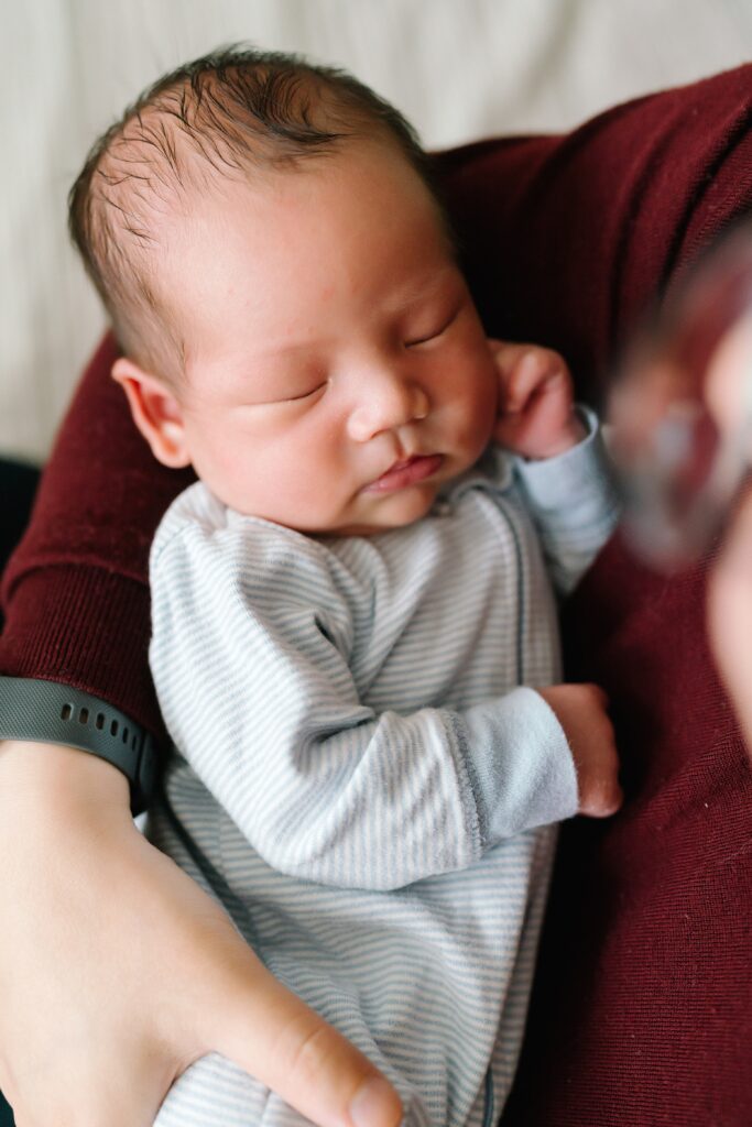 Sleeping newborn baby in father's arms by Bellevue newborn photographer