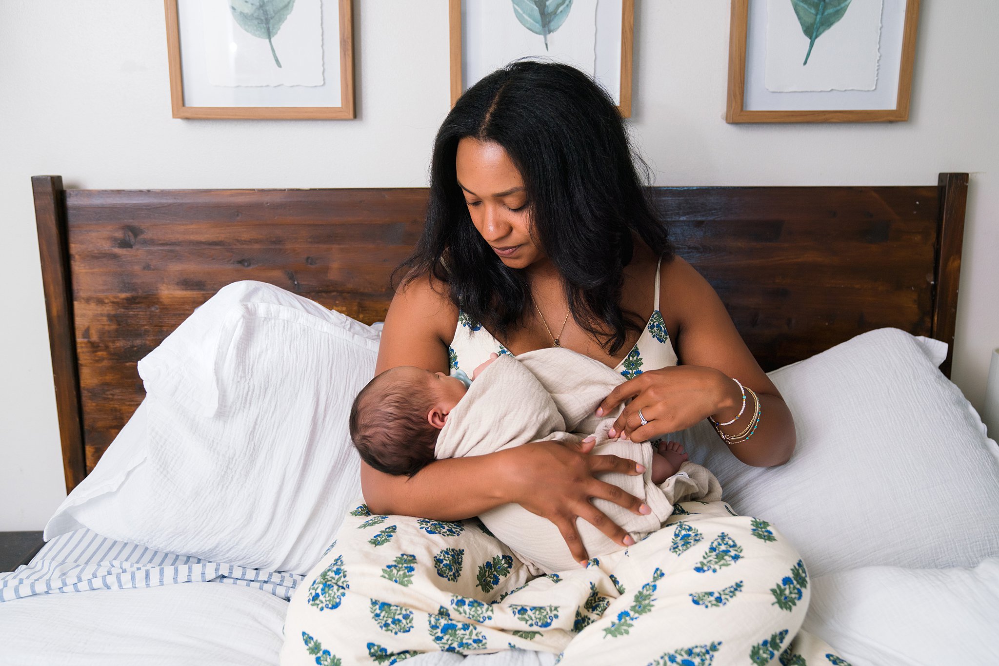 Mother with newborn baby on master bed for photos with Issaquah newborn photographer